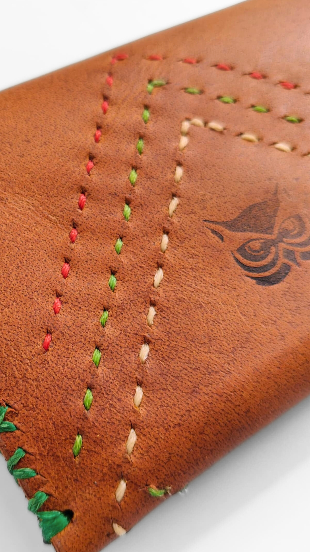 Multi-colour hand-stitching detail on cognac leather with OWL emblem